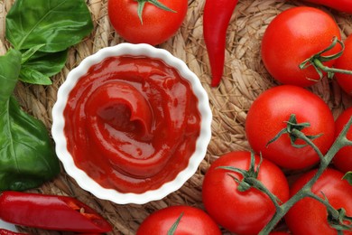 Photo of Bowl of tasty ketchup and ingredients on wicker mat, flat lay