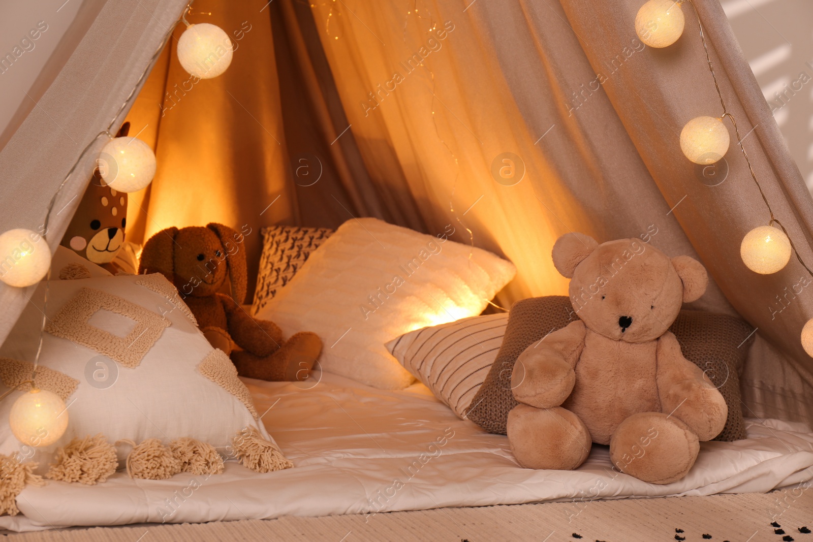 Photo of Play tent with toys and pillows indoors, closeup. Modern children's room interior