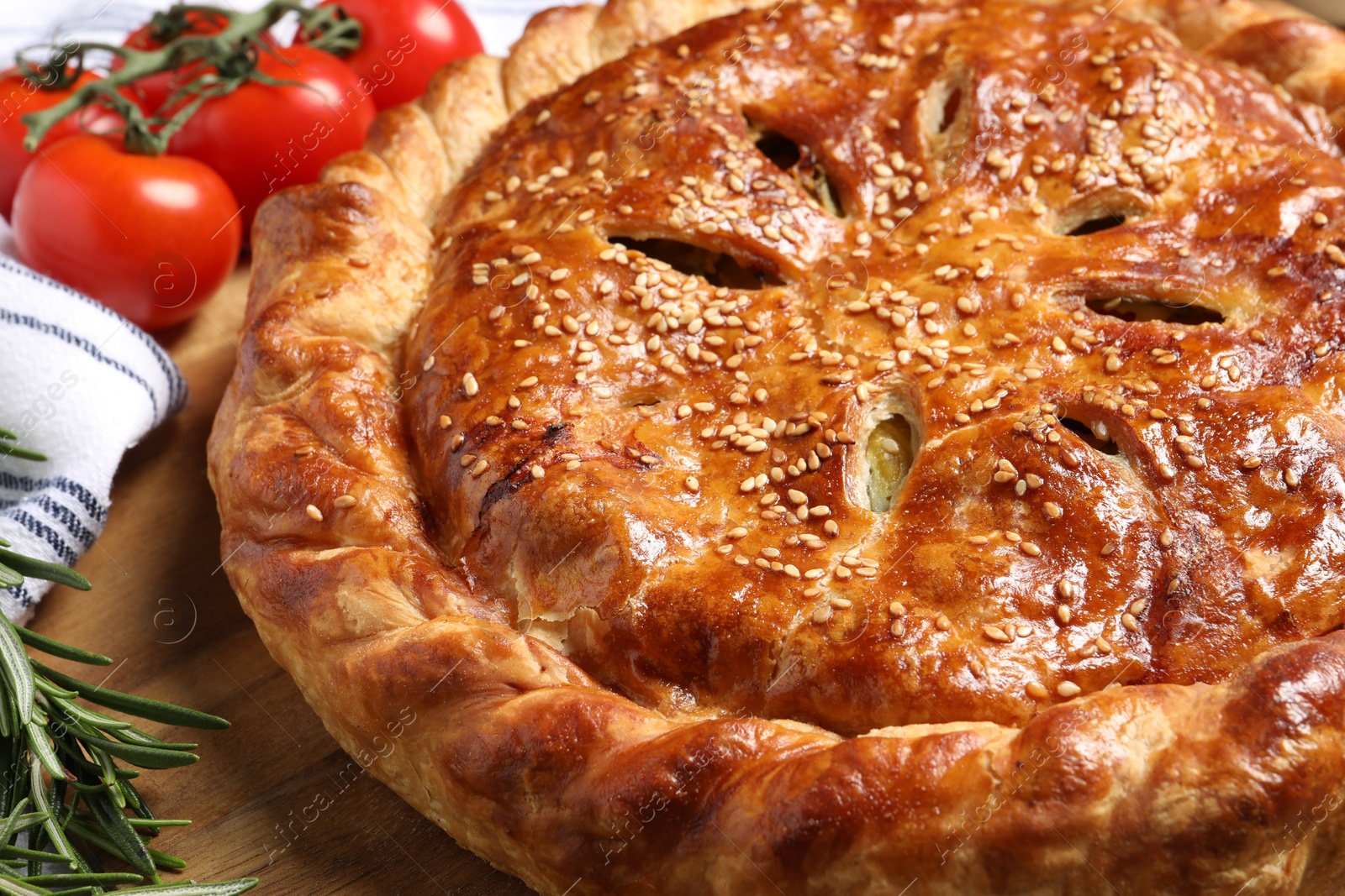 Photo of Tasty homemade pie, rosemary and tomatoes on wooden table