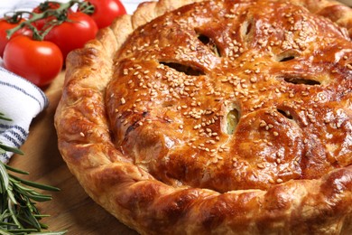 Photo of Tasty homemade pie, rosemary and tomatoes on wooden table