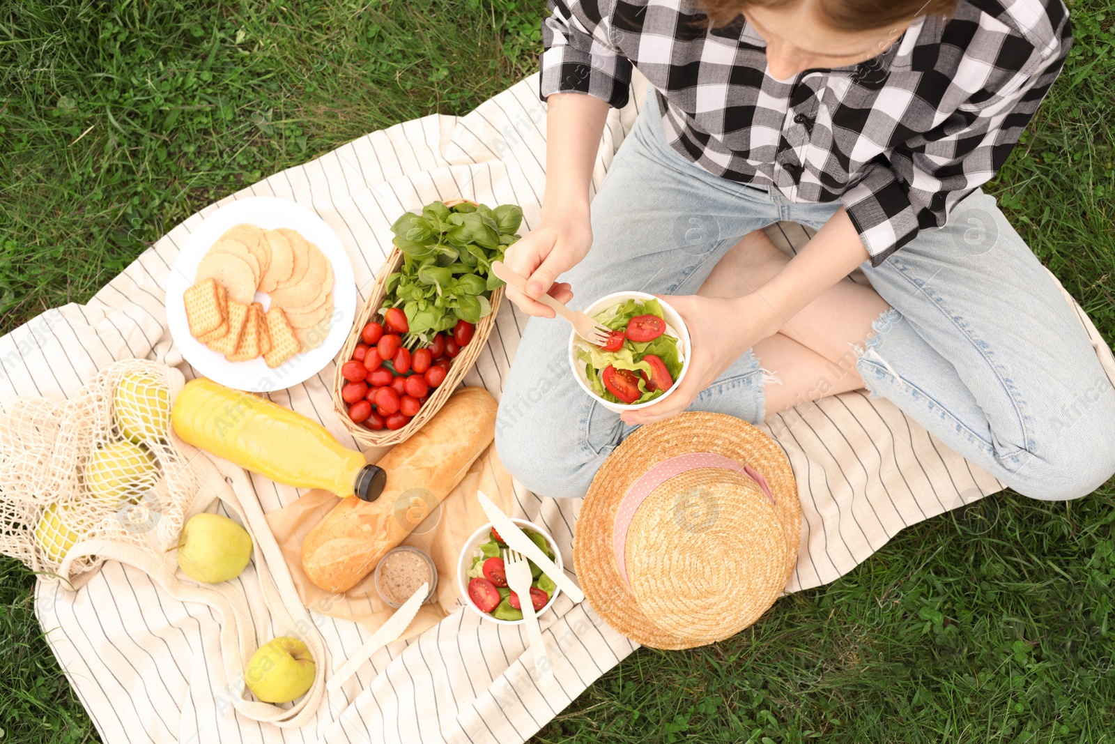 Photo of Girl having picnic on green grass in park, above view