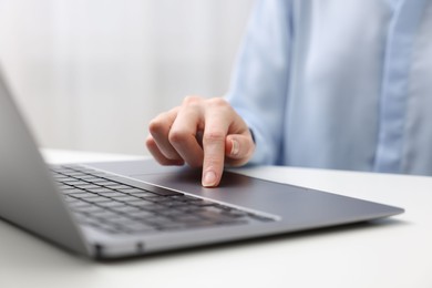 E-learning. Woman using laptop at white table indoors, closeup