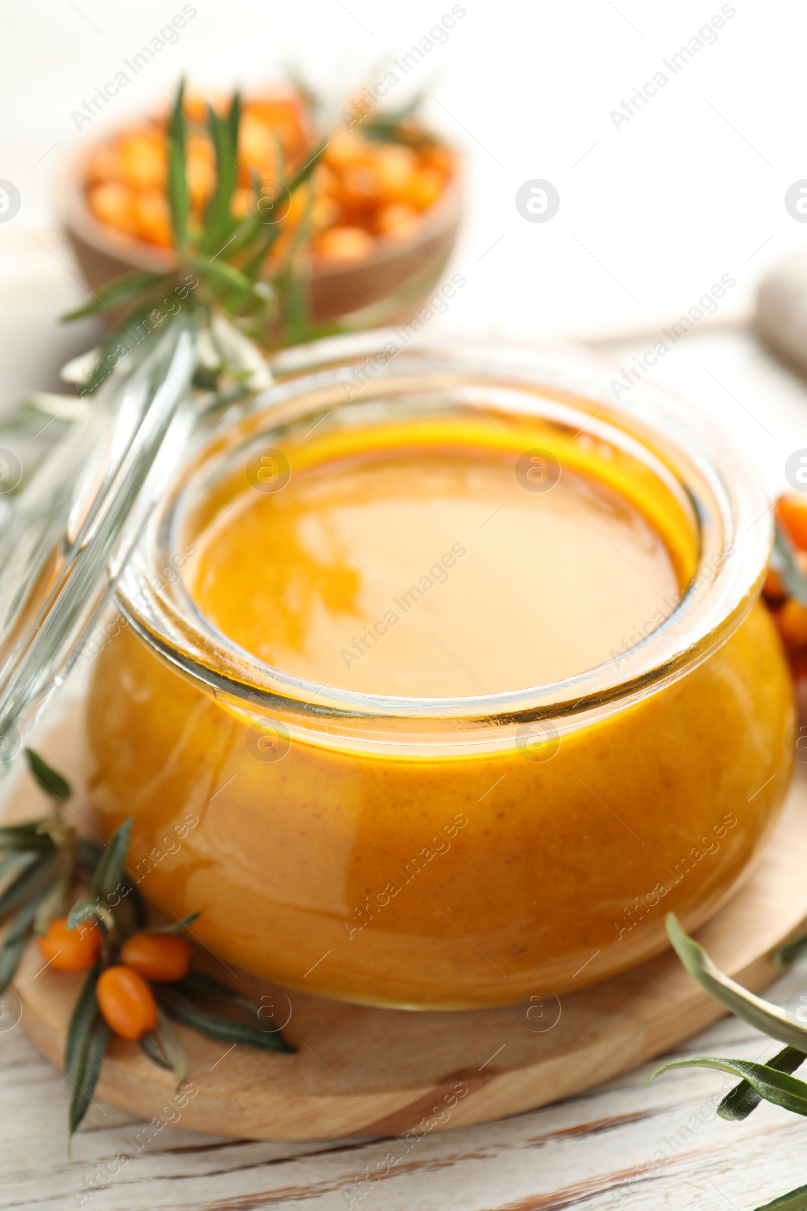 Photo of Delicious sea buckthorn jam and fresh berries on white wooden table, closeup