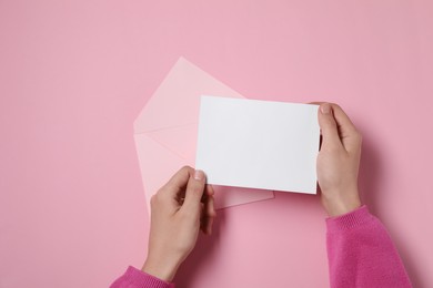 Photo of Woman with blank card at pink table, top view. Space for text