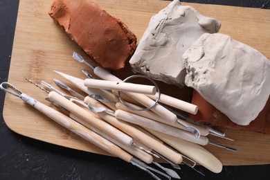 Clay and set of modeling tools on black table, top view