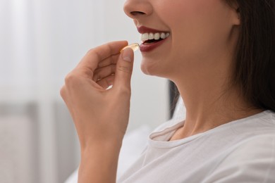 Photo of Woman taking vitamin pill at home, closeup