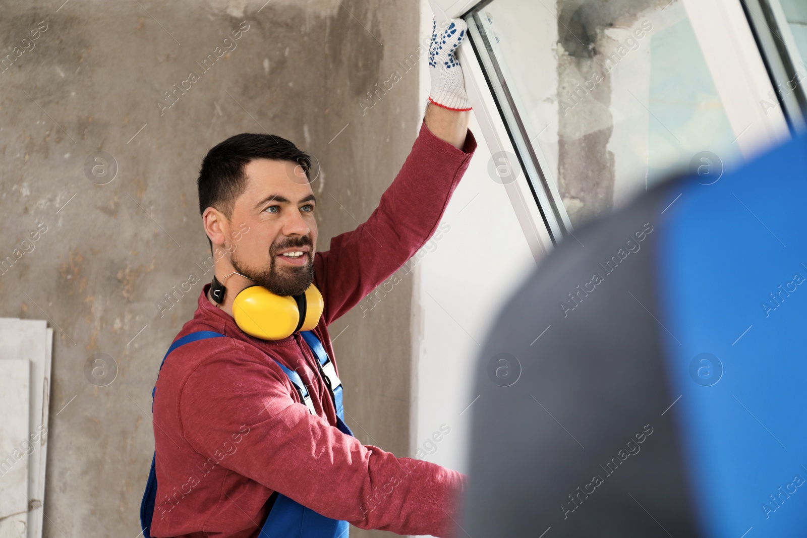 Photo of Workers in uniform installing plastic window indoors