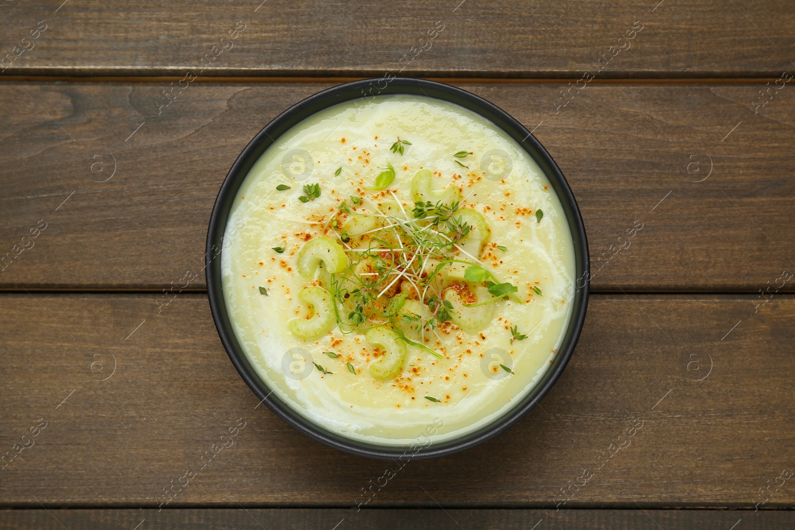 Photo of Bowl of delicious celery soup on wooden table, top view