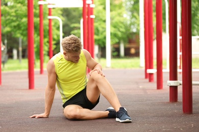 Young man suffering from knee pain on sports ground