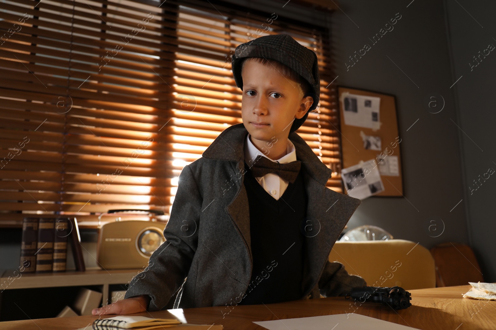 Photo of Cute little detective near table in office