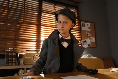 Photo of Cute little detective near table in office