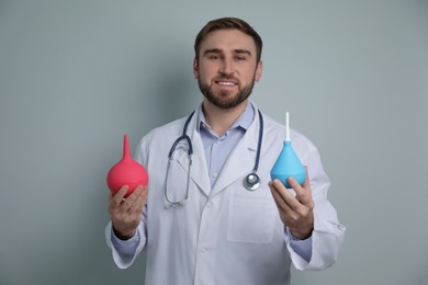 Doctor holding rubber enemas on grey background