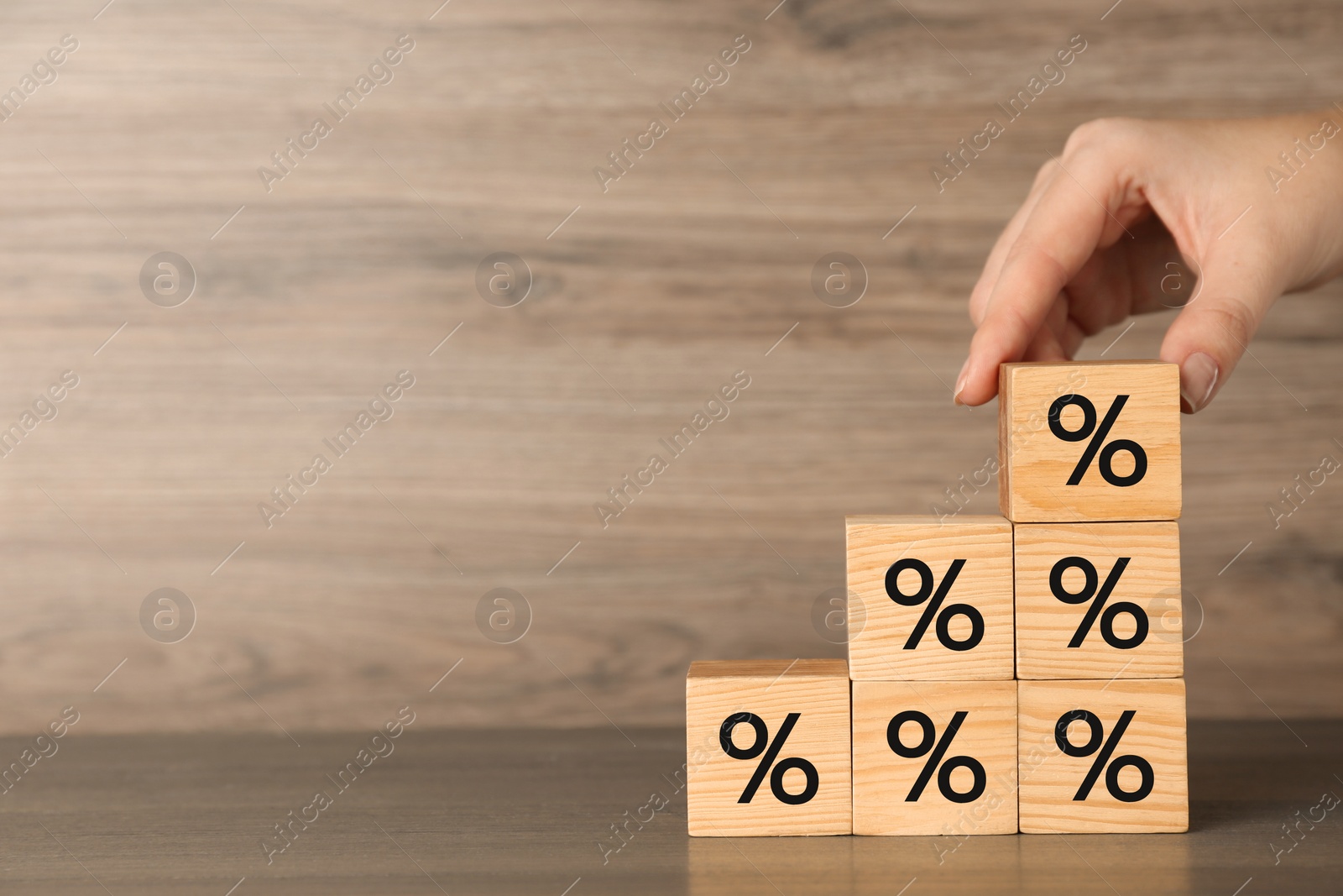 Photo of Woman forming stairs with percent signs at wooden table, closeup. Space for text