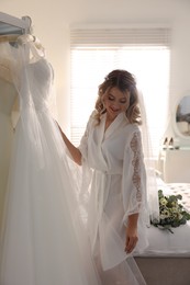 Photo of Beautiful bride with her white wedding dress at home