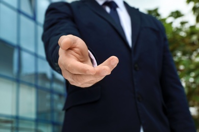Photo of Businessman giving helping hand on blurred background outdoors