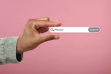 Image of House hunting. Man holding virtual search bar on pink background, closeup