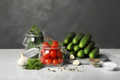 Pickling jars with fresh ripe vegetables and spices on grey table