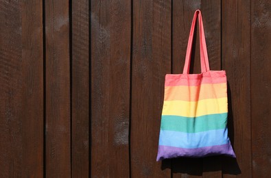 Rainbow bag hanging on wooden background, space for text. LGBT pride
