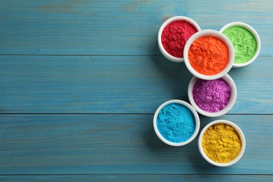 Photo of Colorful powder dyes on light blue wooden background, flat lay with space for text. Holi festival