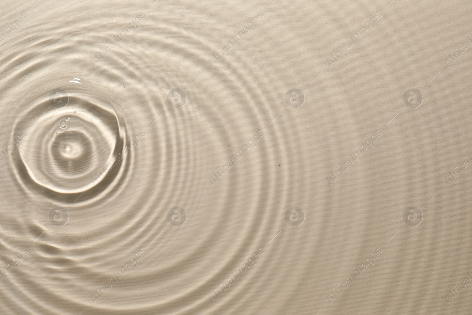 Photo of Rippled surface of clear water on beige background, top view