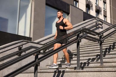 Photo of Man running down stairs outdoors on sunny day. Space for text