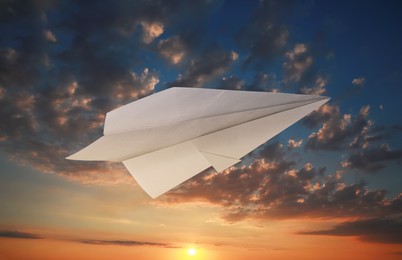 Image of White paper plane and view of beautiful sky at sunset