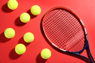 Tennis racket and balls on red background, flat lay. Sports equipment