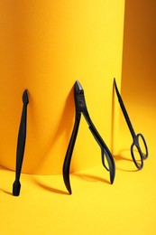 Manicure scissors, cuticle nipper and pusher on yellow background