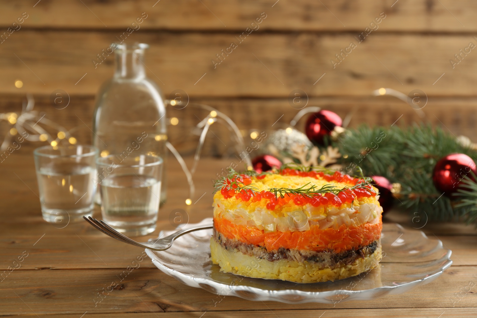 Photo of Traditional russian salad Mimosa and festive decor on wooden table