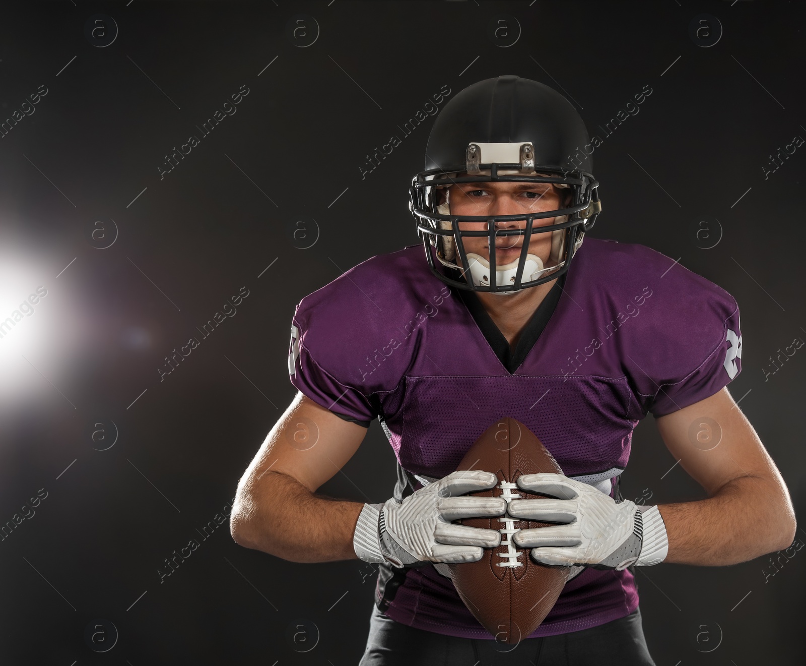 Photo of American football player with ball on dark background