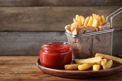 Photo of Tasty French fries served with ketchup on wooden table. Space for text