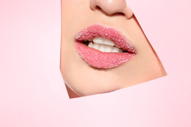 View of beautiful young woman with sugar lips through cutout in color paper
