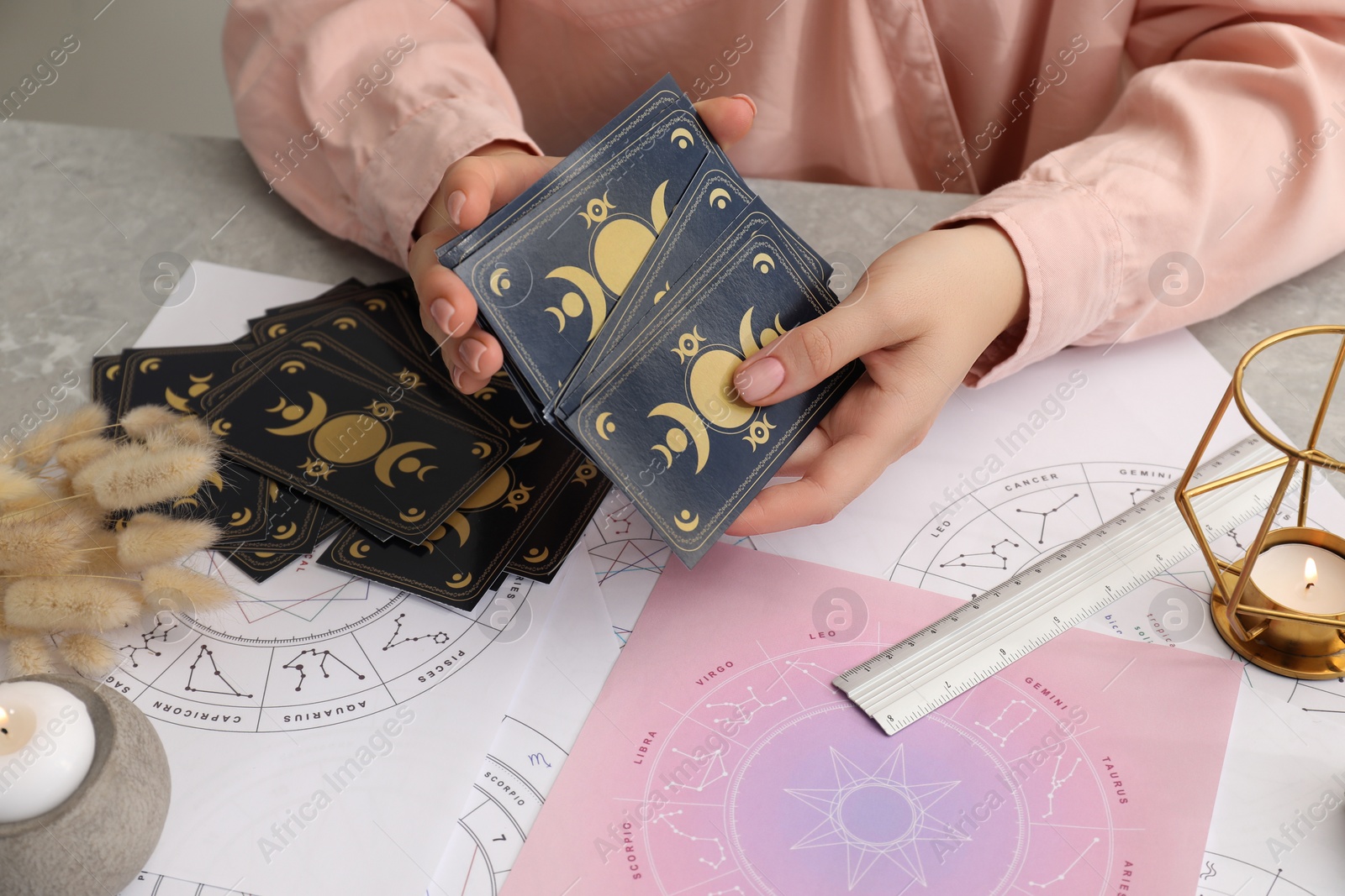 Photo of Woman using tarot cards at table, closeup. Astrological predictions