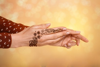 Image of Woman with henna tattoo on hand against blurred background, bokeh effect