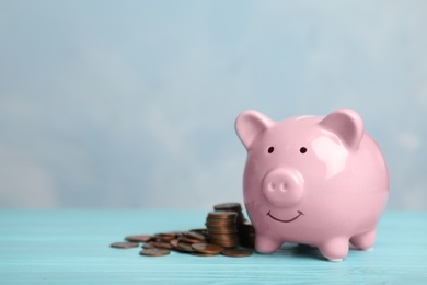 Photo of Cute piggy bank and coins on color table. Space for text