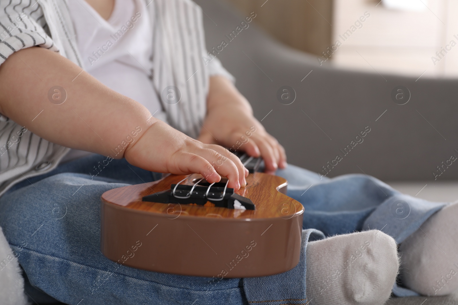 Photo of Little child with toy guitar at home, closeup