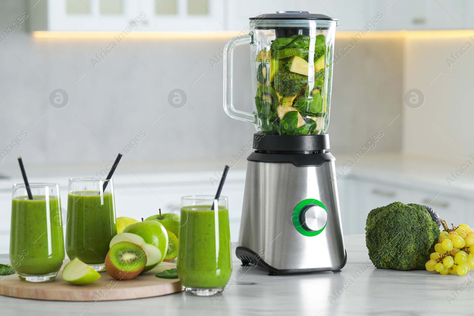 Photo of Delicious fresh smoothie and blender with ingredients on white marble table in kitchen