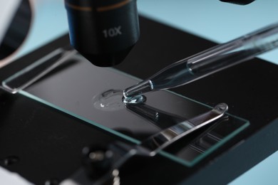 Dripping liquid from pipette onto glass slide on microscope, closeup. Laboratory analysis