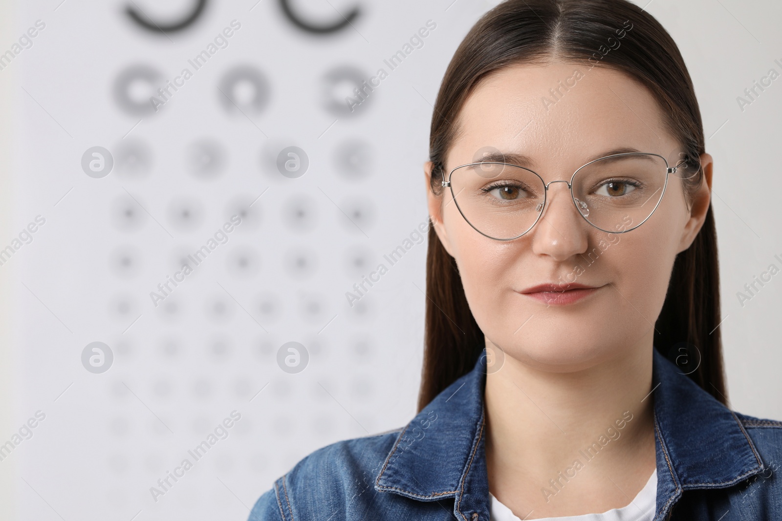 Photo of Young woman with glasses against vision test chart