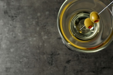 Glass of Classic Dry Martini with olives on grey table, top view. Space for text