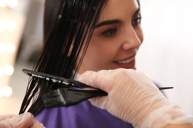 Photo of Professional hairdresser dying hair in beauty salon, closeup