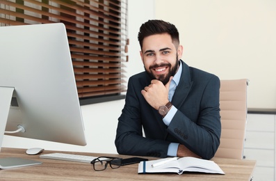 Photo of Handsome businessman working at table in office