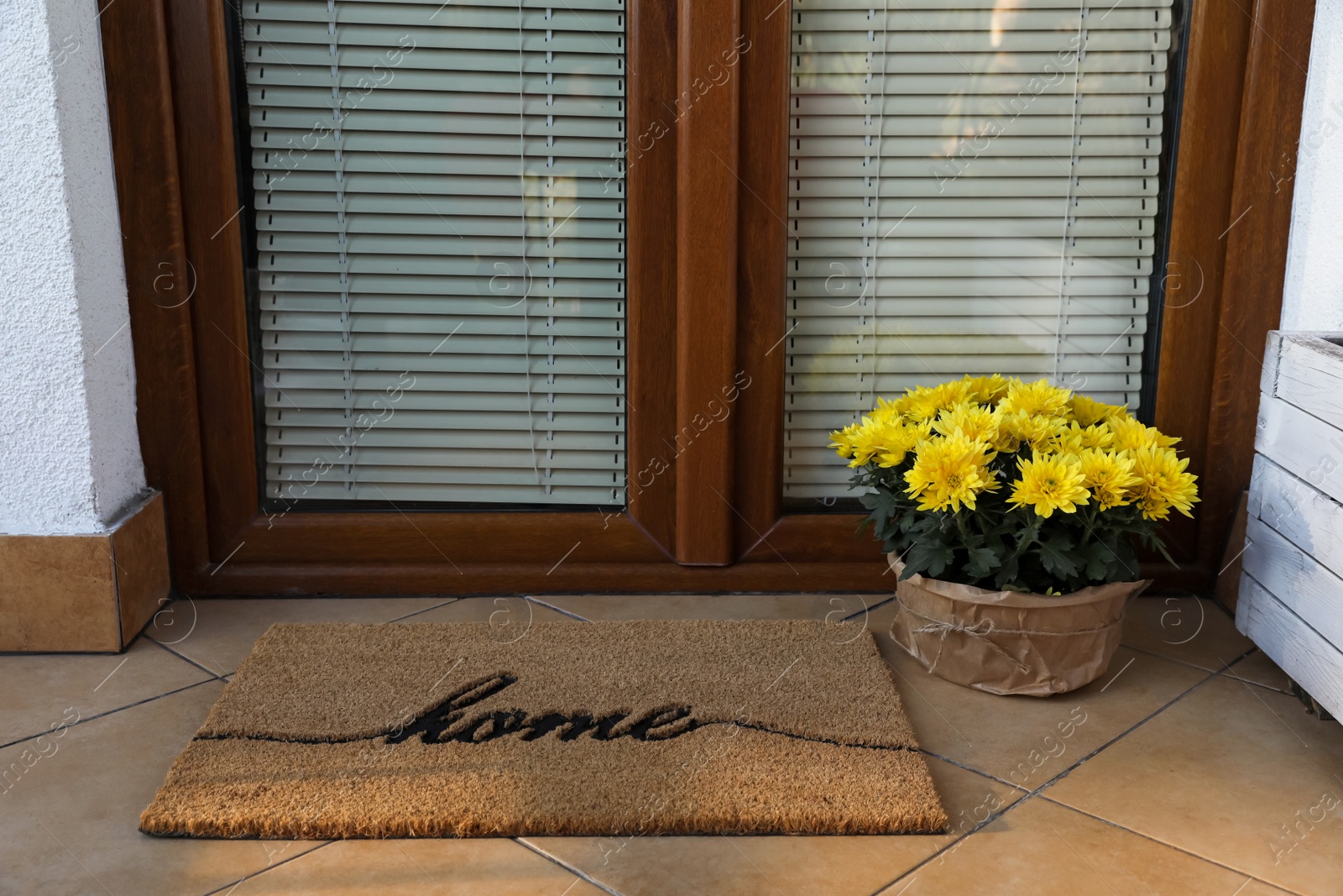 Photo of Doormat with word Home and flowers near entrance outdoors