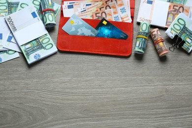 Photo of Wallet, different Euro banknotes and credit cards on wooden table, flat lay with space for text. Money exchange