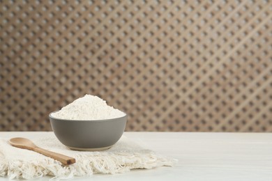 Photo of Ceramic bowl with flour on white wooden table, space for text. Cooking utensils