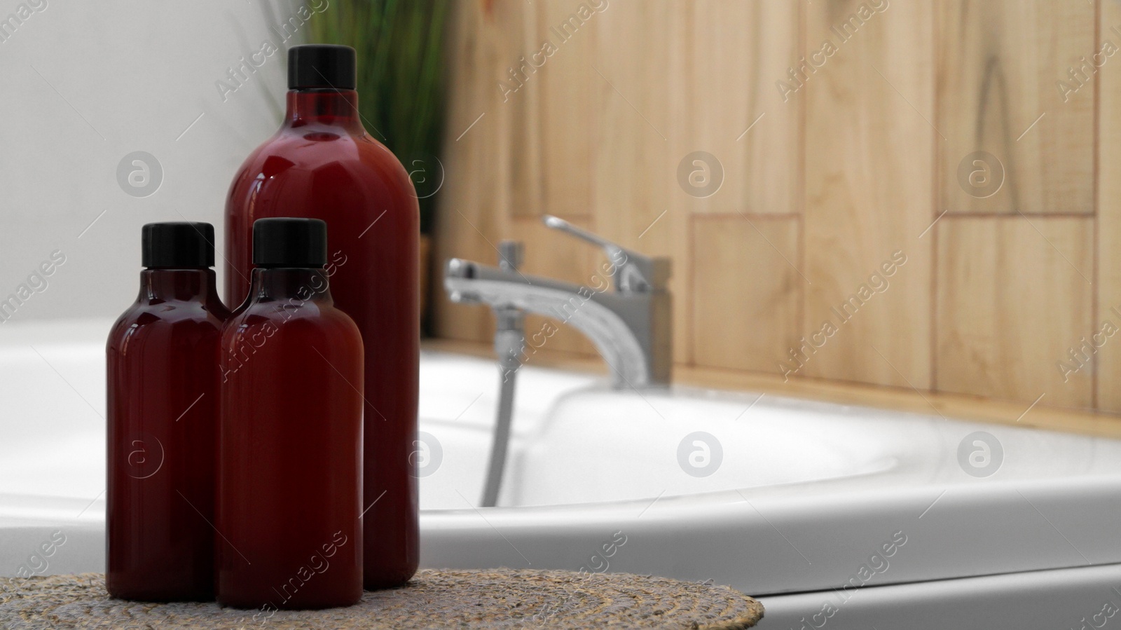 Photo of Bath foam and other personal hygiene products in bottles on wicker mat in bathroom, space for text