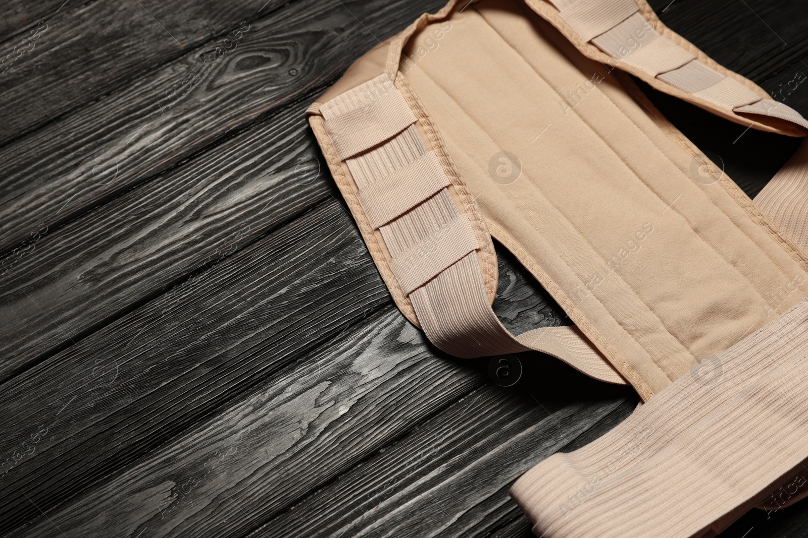 Photo of Beige posture corrector on black wooden table, closeup. Space for text