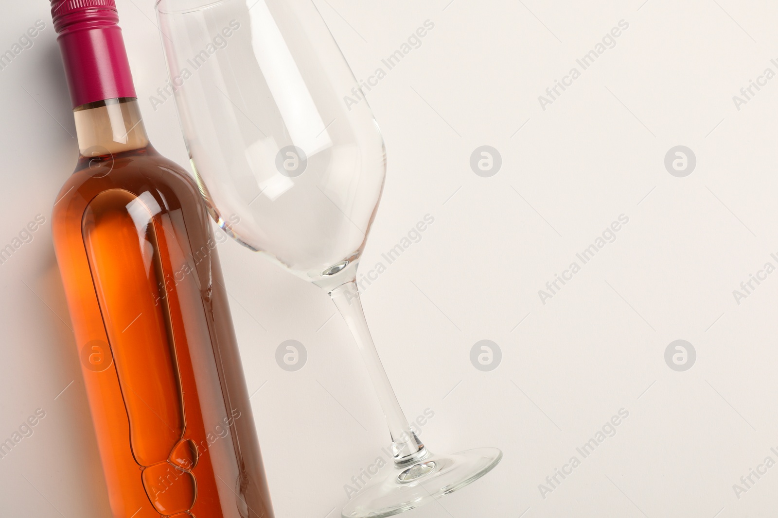 Photo of Bottle of expensive rose wine and wineglass on white background, top view. Space for text