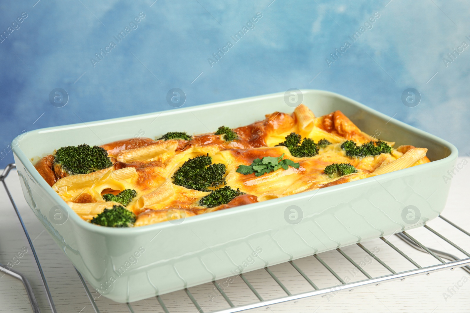 Photo of Tasty broccoli casserole in baking dish on cooling rack