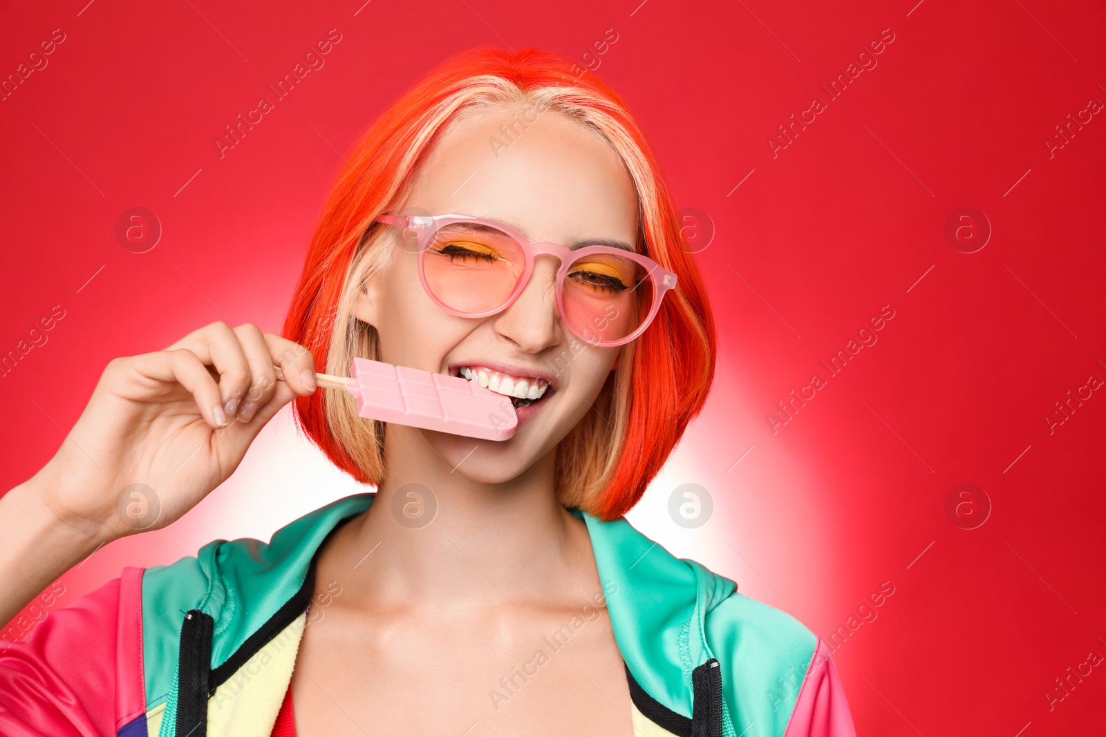 Photo of Beautiful young woman with bright dyed hair eating ice cream on color background